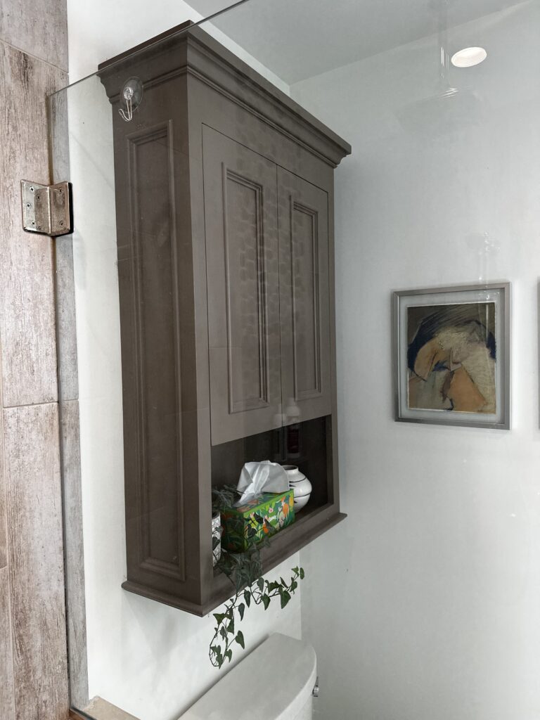 Bathroom wall cabinet. Storage above with open cubbie below. Details include finished paneled sides. Beautiful crown molding and lid. Inset doors on soft close guides. Decorative molding around the flat panels.